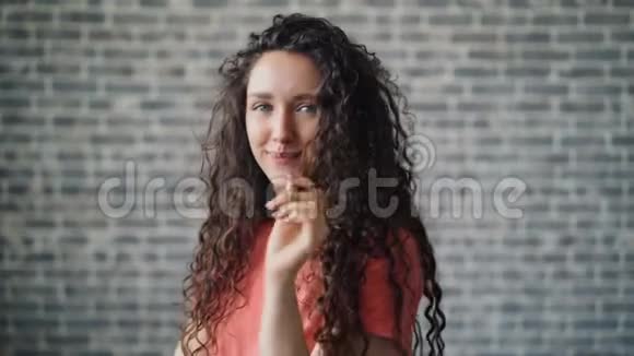 一幅可爱的女人在手指上缠绕着头发在镜头前调情视频的预览图