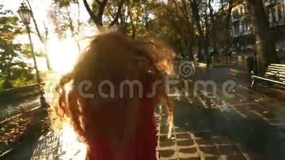美丽的红头发的年轻女子欢快地跑在一个五彩缤纷的秋公园的小巷里欣赏着秋叶视频的预览图