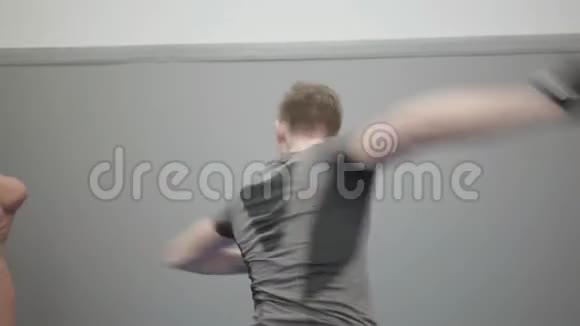 一位戴手套拳打脚踢的职业年轻人的肖像展示了他在健身房的技能视频的预览图