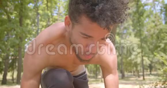 年轻的赤膊非洲男性慢跑者准备在公园里跑步的特写镜头户外运动视频的预览图