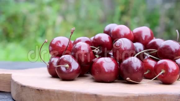 成熟的红色樱桃浆果天然绿色背景和木制桌子慢动作特写视频的预览图