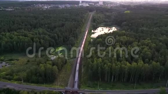 在俄罗斯卡雷利亚的湖泊和森林中的双线铁路上经过一段距离的货运列车空中景观视频的预览图