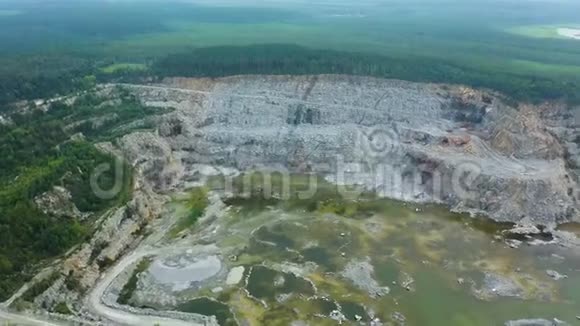 露天采石场的俯视图用工作卡车在露天坑上站立的灰色灰尘的全景采矿业概念视频的预览图