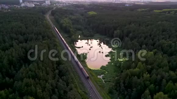 在树林里的乌拉尔沼泽湖上火车用煤和一辆电力机车载着火车空中摄影视频的预览图