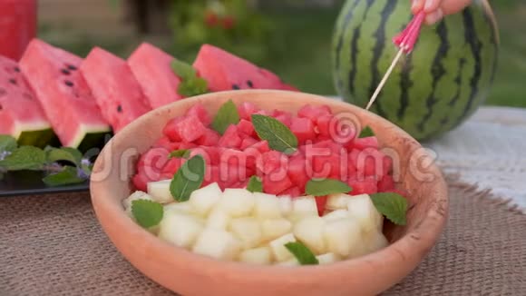 手从盘子里拿西瓜和麝香的小正方体夏季清爽水果沙拉接近视频的预览图