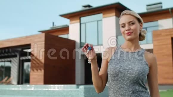 兴奋的女人拿着钥匙站在别墅附近漂亮的女人拿着钥匙视频的预览图