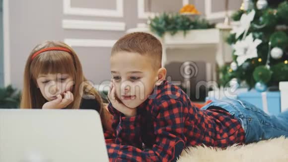 快乐的孩子们正在装饰新年的房间里用笔记本电脑玩现代有趣的游戏视频的预览图