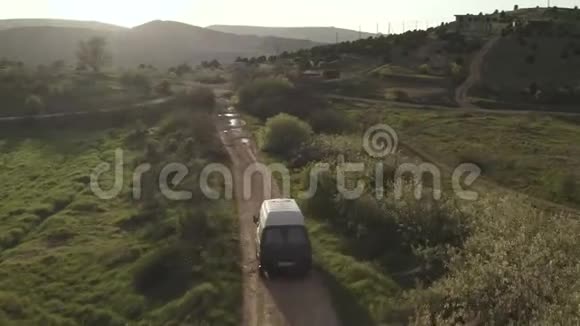 旅游汽车在灌木丛和田野之间蜿蜒的道路上行驶空中景观视频的预览图