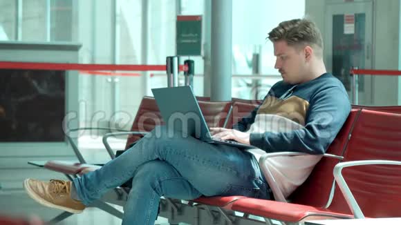 年轻人坐在机场等候区手提电脑视频的预览图