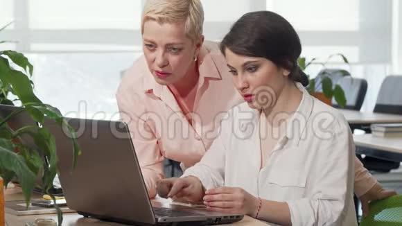 年轻的女商人向女老板展示她在笔记本电脑上的项目视频的预览图