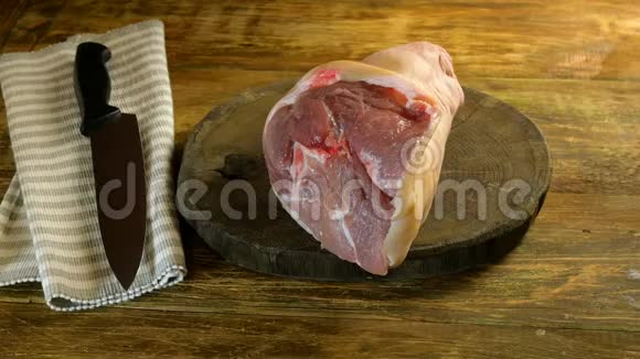 屠夫用钝斧在深色的木桌上切生猪肉小腿以便进一步烹饪或销售特写镜头视频的预览图