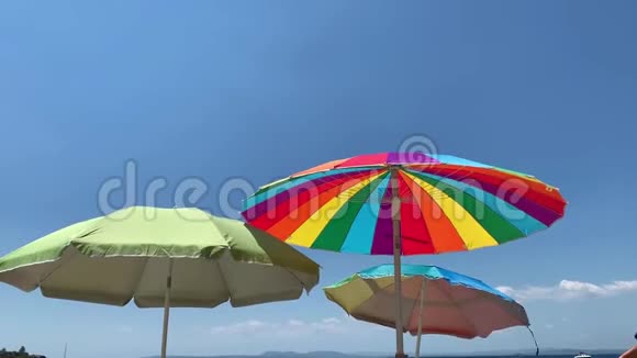 海滩上三把鲜艳的太阳伞视频的预览图