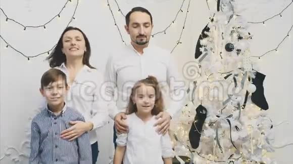 爱的父母和小孩子站在圣诞树附近摆姿势竖起大拇指视频的预览图