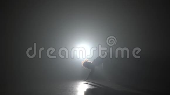 运动女孩在黑暗中练习卡波伊拉对抗演播室的聚光灯视频的预览图