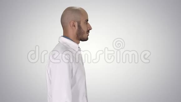 穿着白色长袍的阿拉伯医生在梯度背景下行走视频的预览图