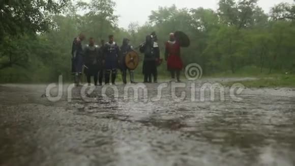 中世纪十字军骑士在雨中穿过森林道路上的水坑视频的预览图