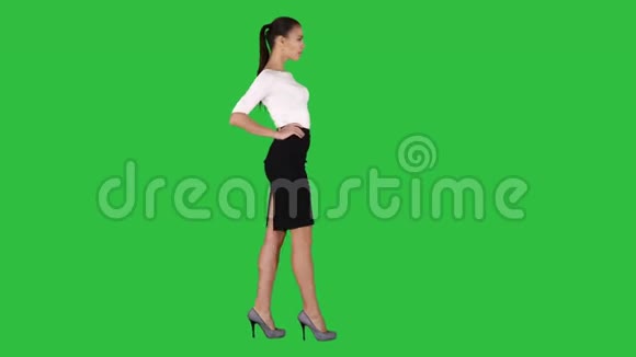 美丽的年轻女子穿着优雅的服装行走双手握在绿色屏幕上的臀部色度键视频的预览图