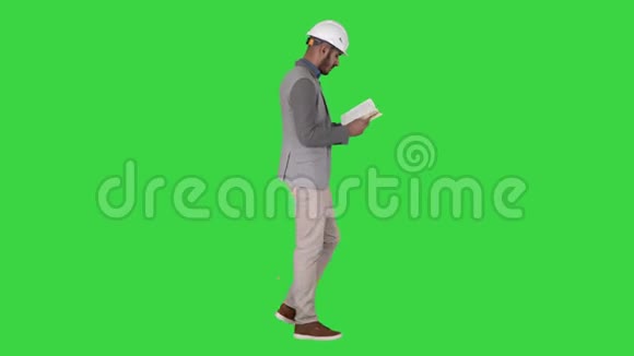 年轻建筑师一边阅读课本或笔记本一边走在绿色的屏幕上色度键视频的预览图