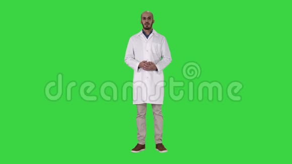 穿着医用外套的阿拉伯医生用手在绿色屏幕上展示一些东西Chroma键视频的预览图