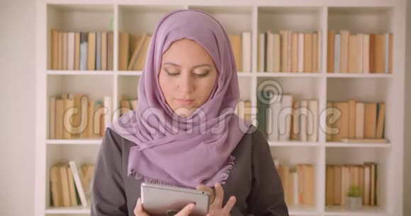 使用平板电脑特写穆斯林年轻漂亮女性的照片并在镜头中显示绿色彩色屏幕视频的预览图