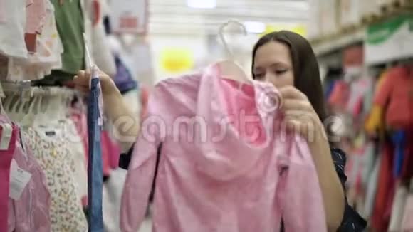 在超市购物中心商场里一个漂亮的女孩为孩子挑选衣服孩子们的衣服视频的预览图