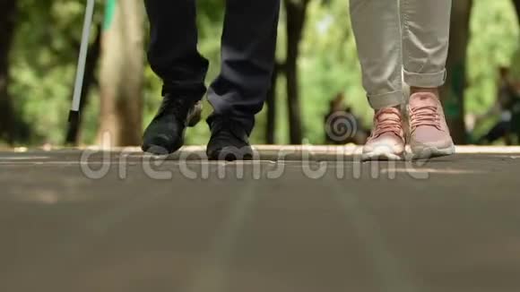孙女带着拐杖慢慢地和爷爷一起走在公园里视频的预览图