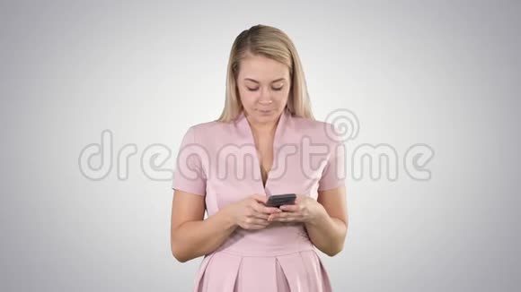 微笑的年轻女士在梯度背景下的手机上阅读短信的肖像视频的预览图