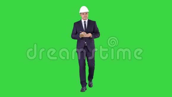 工程师西装和头盔行走和写笔记在记事本上的绿色屏幕色度键视频的预览图