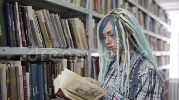 女时髦的大学生戴着恐惧症在书架上找书视频的预览图