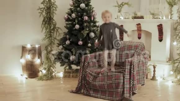在圣诞节装饰的背景下小女孩跳上了新年的椅子视频的预览图
