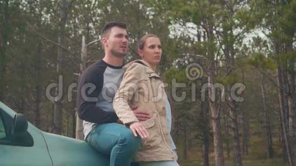 一对年轻夫妇一个男人和一个女孩站在森林里的一辆车上他们在说话视频的预览图