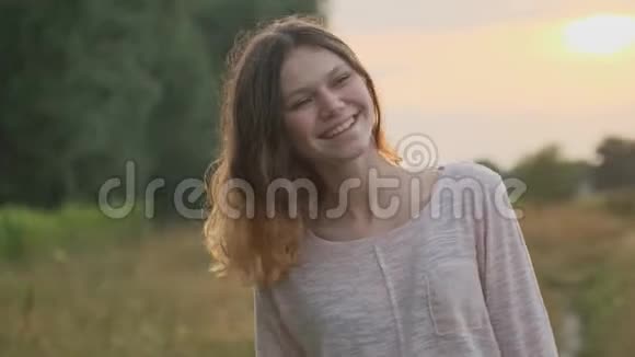 15岁的少女带着棕色的长发看着镜头她美丽欢快的笑着画像视频的预览图