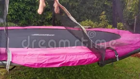 女性成人在蹦床上跳跃脚和腿在特写有趣的户外运动在花园里视频的预览图
