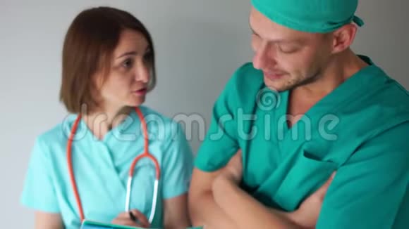 医护人员上班期间一男一女身穿绿色医用礼服正在讨论病人治疗计划视频的预览图