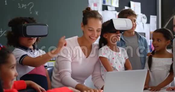 使用虚拟现实耳机与老师和同学i4k的混合种族学龄儿童的正面视图视频的预览图