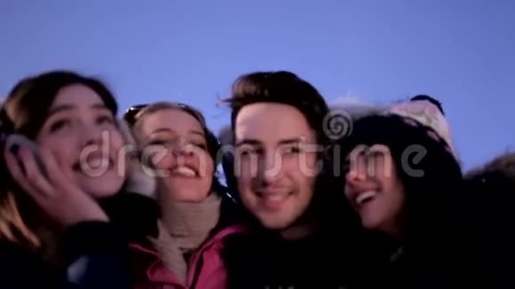三个有趣的女孩和一个男人在一个晴朗的冬天的蓝天背景视频的预览图