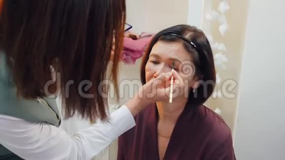 化妆师用化妆刷给老妇人化妆眉毛视频的预览图