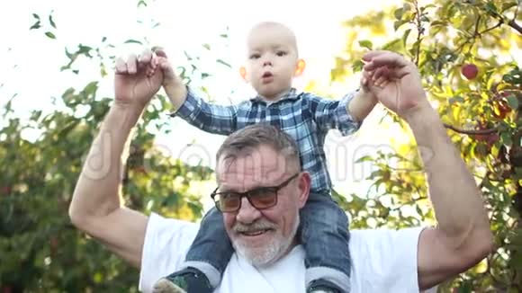 戴着胡子和眼镜的快乐爷爷扶着小孙子的肩膀托德勒高兴地笑了视频的预览图