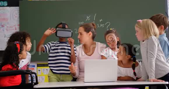 非裔美国小学生使用虚拟现实耳机与老师和同学I的正面视图视频的预览图