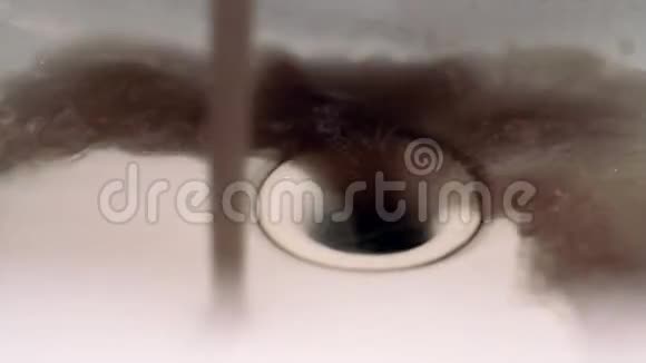关闭从水槽中的水龙头流出的肮脏生锈的棕色污染水视频的预览图