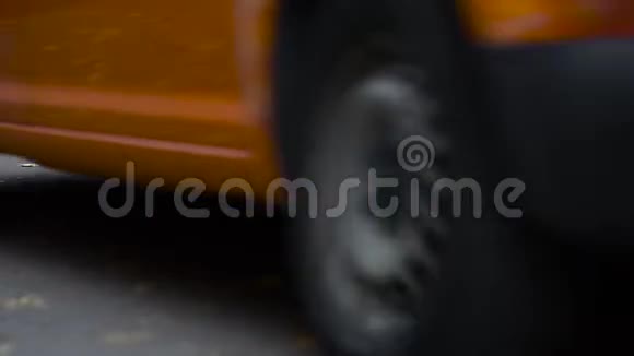 一辆橙色的汽车驶过一条布满黄色落叶的道路秋天视频的预览图