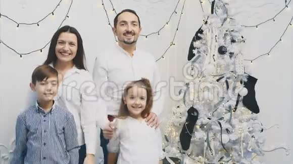 爱的父母和小孩子站在圣诞树附近摆姿势竖起大拇指视频的预览图