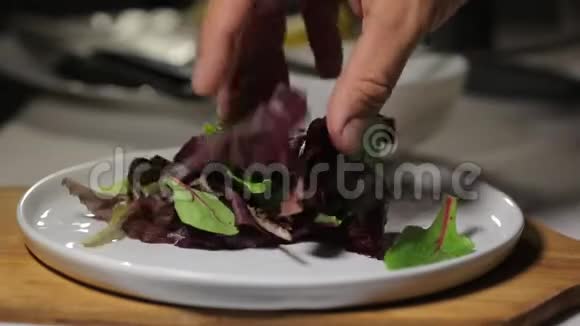 厨师用新鲜的有机蔬菜和树叶做沙拉然后倒入橄榄油酱视频的预览图