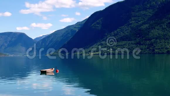 停泊在红色浮标上的小木船漂浮在挪威的Lustrafjord水域上倒影着群山和蓝天视频的预览图