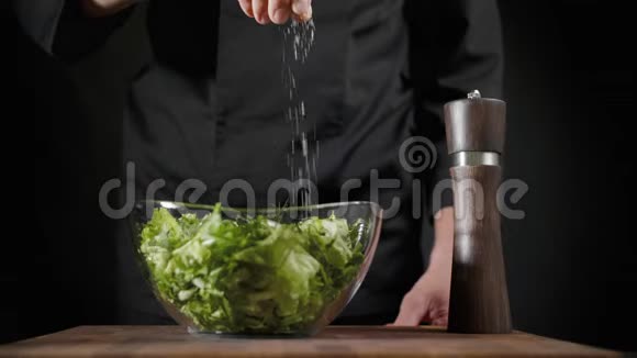 将盐和香料洒在黑色背景的绿色沙拉上视频的预览图