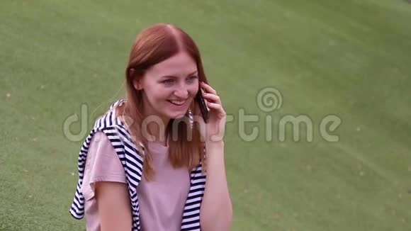 坐在公园的长凳上用手机说话的年轻女孩视频的预览图