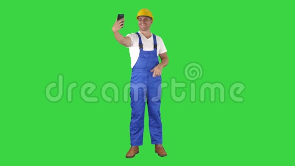 微笑英俊的年轻建筑工用手机在绿色屏幕上自拍Chroma键视频的预览图