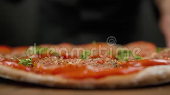 厨师在黑色的背景上为比萨饼洒上格林利视频的预览图