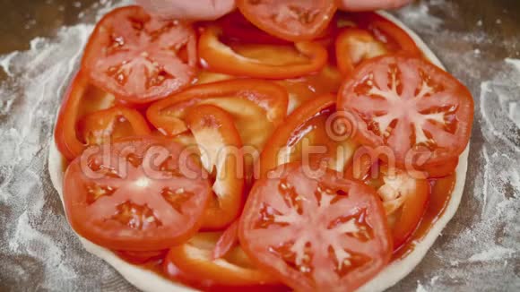 一个男人把西红柿放在面团上做披萨双手合拢视频的预览图