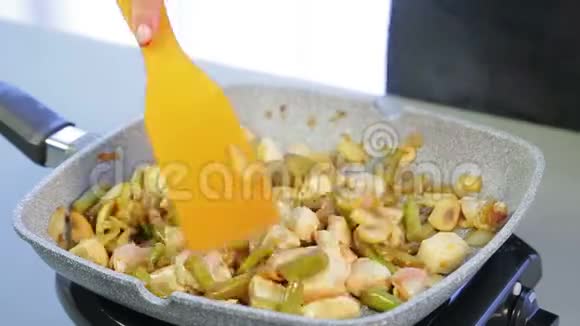 一个女人在煎锅里把木铲和鸡片和豆子和蘑菇混合在一起时光飞逝视频的预览图